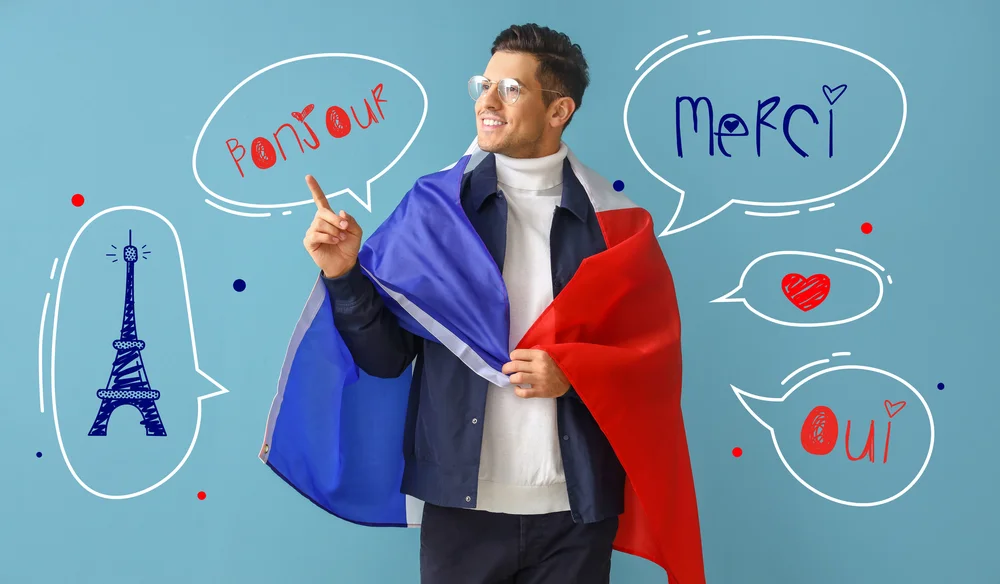 Man draped in French flag, pointing, speech bubbles show "Bonjour," "Merci," "Oui," Eiffel Tower